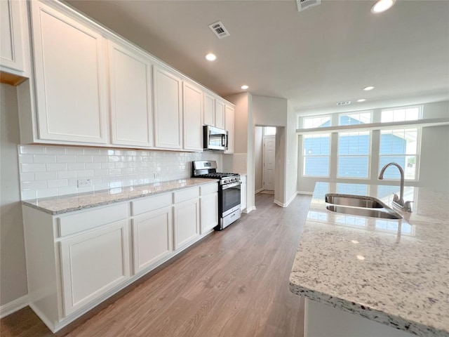 431 Ferrule Dr, Kyle, TX 78640 - kitchen featuring stainless steel appliances, a sink, white cabinetry, tasteful backsplash, and baseboards