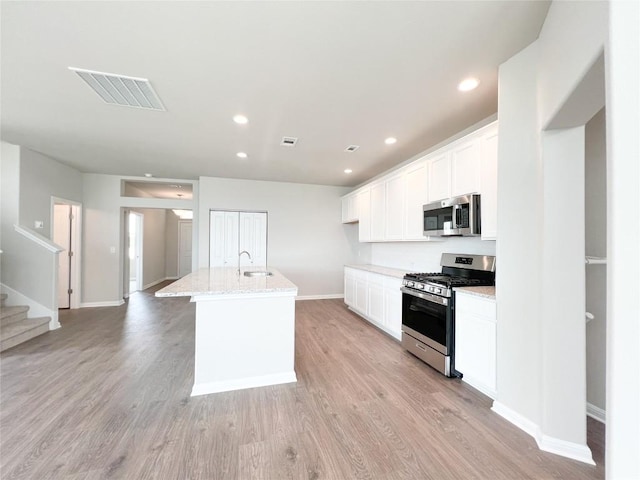431 Ferrule Dr, Kyle, TX 78640 - kitchen featuring appliances with stainless steel finishes, white cabinetry, an island with sink, light wood-style floors, and recessed lighting