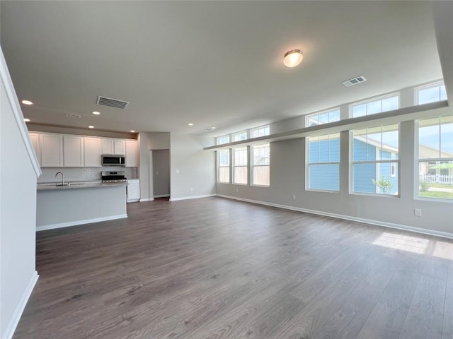 431 Ferrule Dr, Kyle, TX 78640 - unfurnished living room with baseboards, dark wood finished floors, recessed lighting, and a sink