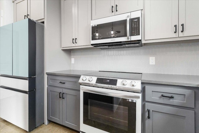 114 Shady Bluff Dr, Wimberley, TX 78676 - kitchen with stainless steel appliances, gray cabinets, backsplash, and light countertops