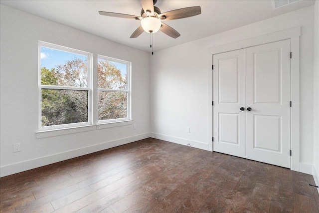 114 Shady Bluff Dr, Wimberley, TX 78676 - unfurnished bedroom with baseboards, dark wood finished floors, a closet, and a ceiling fan