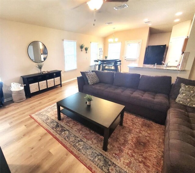 130 Navidad River Dr, Hutto, TX 78634 - living room featuring wood finished floors, a ceiling fan, baseboards, lofted ceiling, and a chandelier