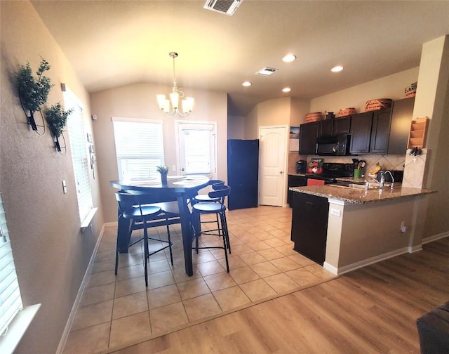 130 Navidad River Dr, Hutto, TX 78634 - kitchen with black appliances, a sink, a chandelier, light stone counters, and a peninsula