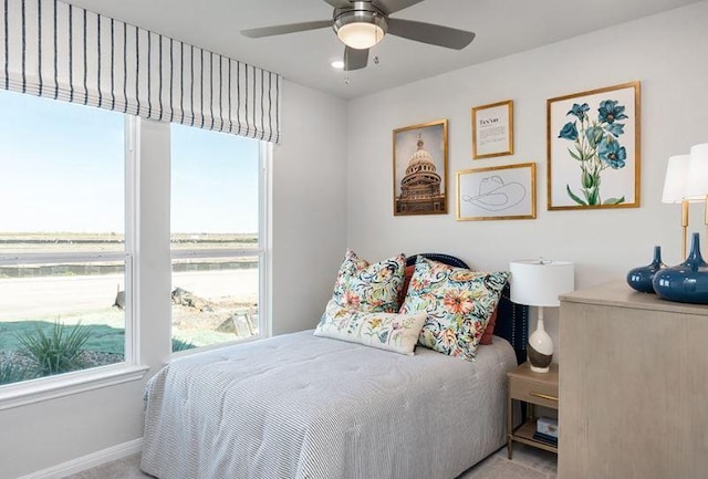 bedroom with multiple windows, baseboards, a ceiling fan, and carpet flooring