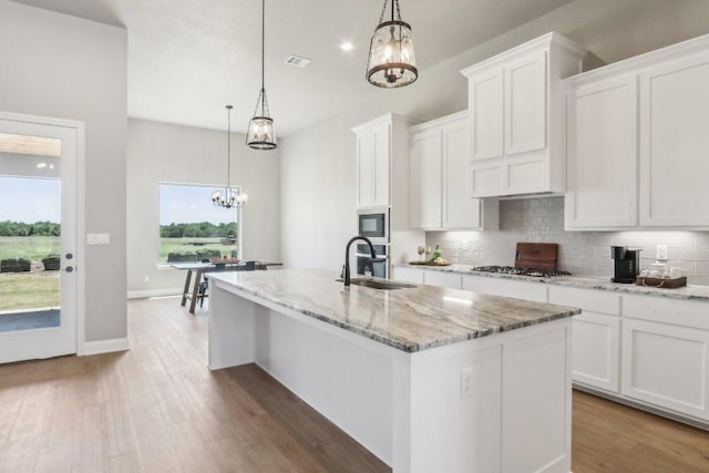 4007 Aerie St, Salado, TX 76571 - kitchen featuring a chandelier, a sink, a center island with sink, backsplash, and white cabinets