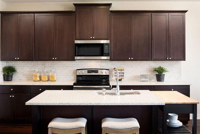 4005 Wynn Rd, Hutto, TX 78634 - kitchen featuring appliances with stainless steel finishes, a sink, a kitchen breakfast bar, and light stone counters