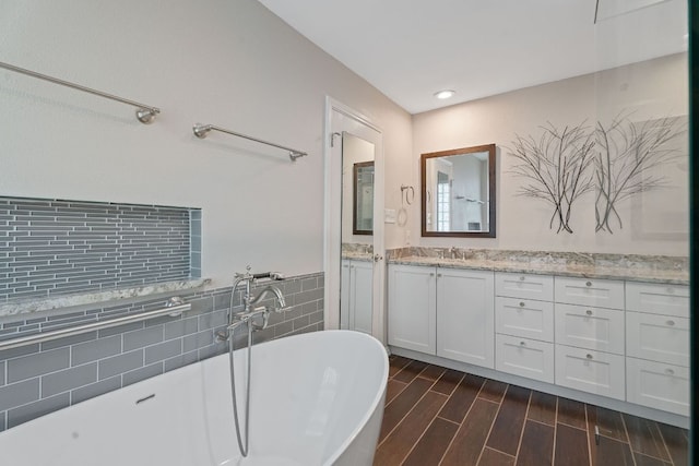 10109 Vaquero Trl, Austin, TX 78759 - bathroom featuring vanity, tile walls, a freestanding tub, wood finished floors, and a wainscoted wall