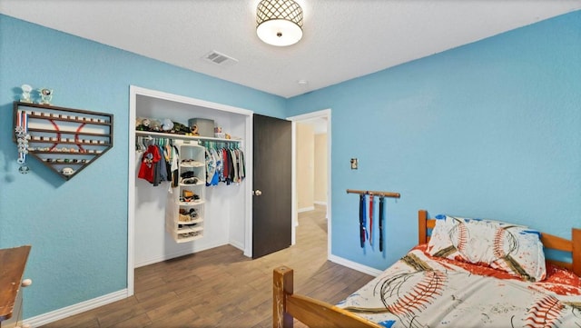 bedroom featuring wood finished floors, a closet, and baseboards