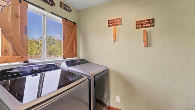 laundry area with washer and dryer, a barn door, and a textured wall