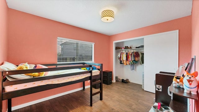 bedroom featuring wood finished floors, a closet, and baseboards