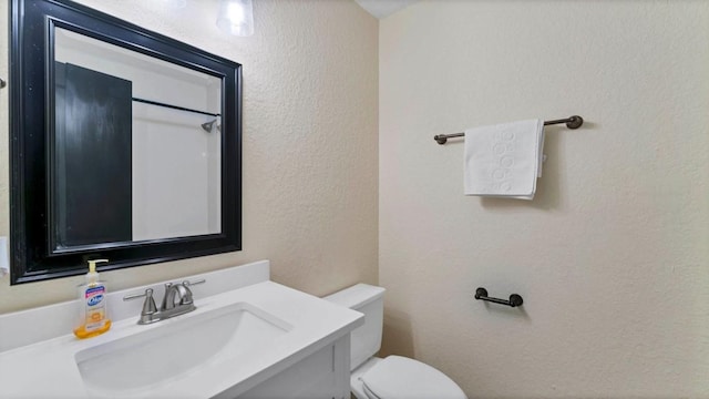 bathroom featuring a sink, toilet, and a textured wall