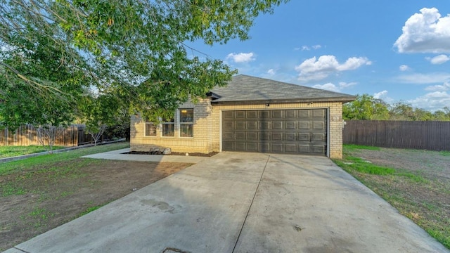 view of front facade with a garage, fence, brick siding, and driveway