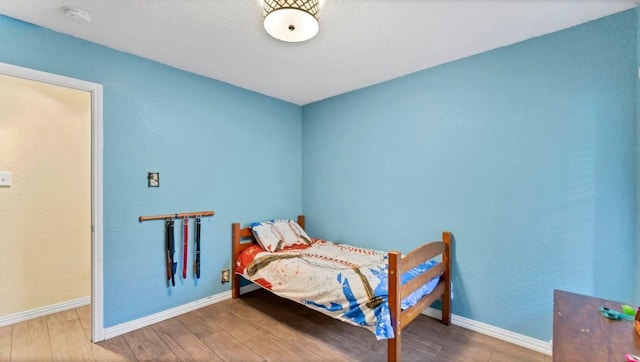 bedroom with wood finished floors and baseboards