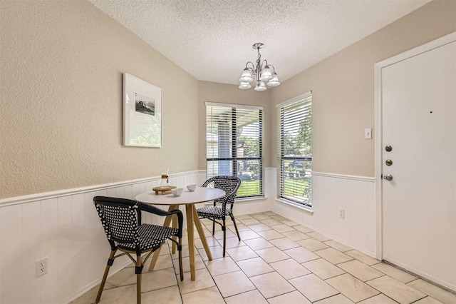 1711 Provident Ln, Round Rock, TX 78664 - dining space featuring a chandelier, a textured ceiling, a wainscoted wall, a textured wall, and light tile patterned floors