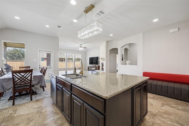 kitchen featuring a sink, open floor plan, recessed lighting, dark brown cabinetry, and light stone counters