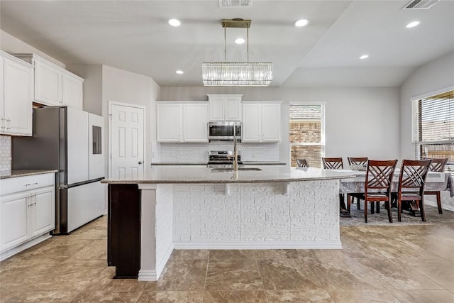 kitchen featuring stainless steel microwave, freestanding refrigerator, plenty of natural light, a sink, and recessed lighting