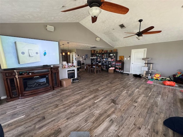 21424 Martin Ln, Pflugerville, TX 78660 - living room with a ceiling fan, lofted ceiling, wood finished floors, a textured ceiling, and a fireplace