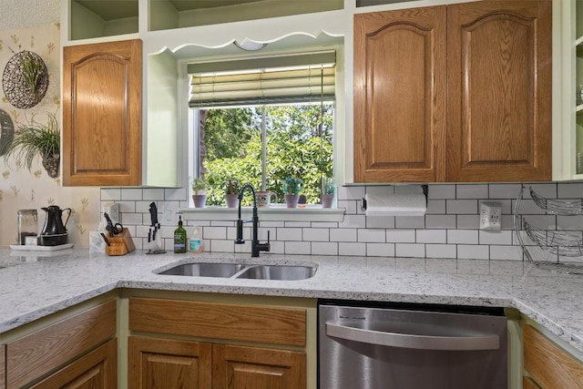 kitchen featuring stainless steel dishwasher, a sink, backsplash, and light stone countertops