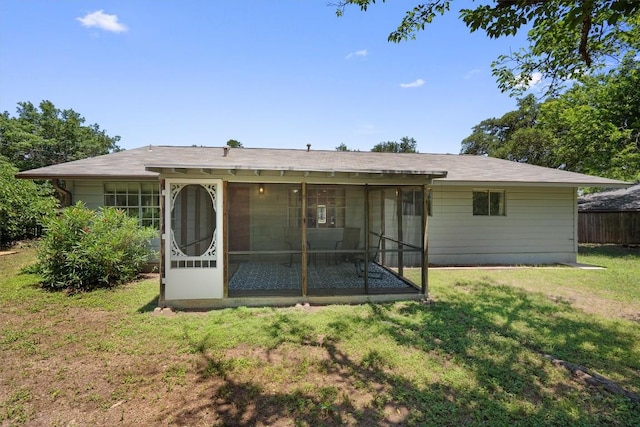 rear view of property featuring a sunroom and a lawn