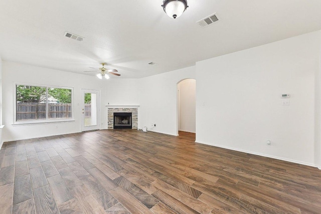 13213 Marie Ln, Manor, TX 78653 - unfurnished living room featuring ceiling fan, dark wood-style flooring, arched walkways, a fireplace, and baseboards