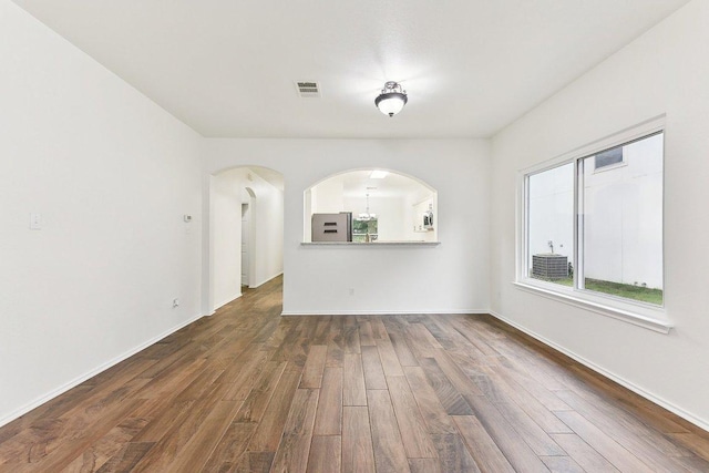 13213 Marie Ln, Manor, TX 78653 - unfurnished living room featuring dark wood finished floors, arched walkways, and baseboards