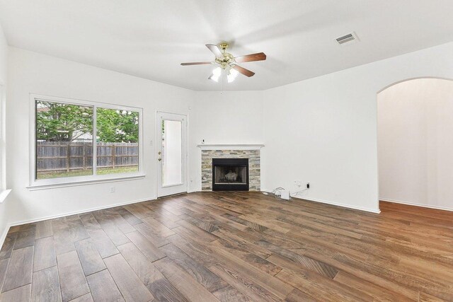 13213 Marie Ln, Manor, TX 78653 - unfurnished living room featuring wood finished floors, arched walkways, ceiling fan, and a fireplace