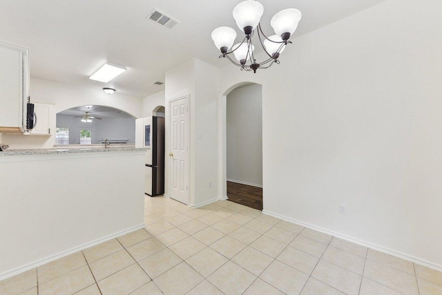 13213 Marie Ln, Manor, TX 78653 - spare room featuring arched walkways, a chandelier, ceiling fan, light tile patterned flooring, and baseboards