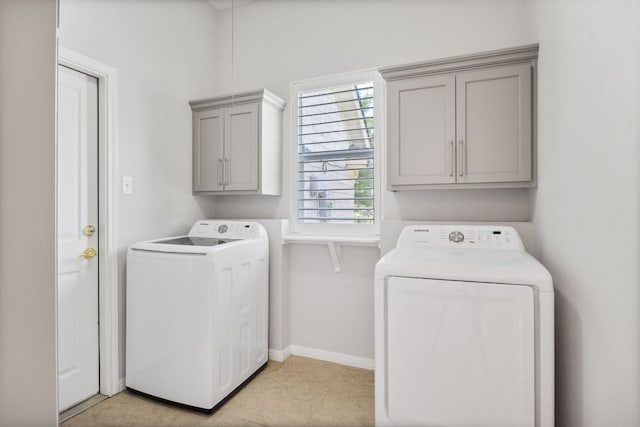clothes washing area featuring washing machine and dryer, baseboards, and cabinet space