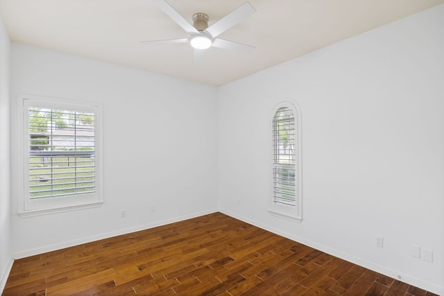 unfurnished room featuring plenty of natural light, dark wood-style flooring, ceiling fan, and baseboards