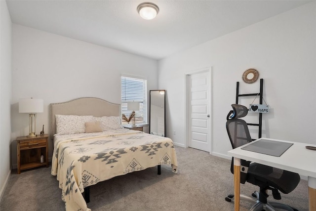 carpeted bedroom featuring an office area and baseboards