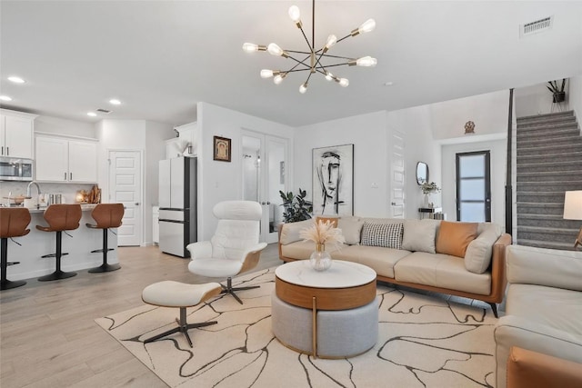 living room featuring light wood finished floors, stairs, a chandelier, and recessed lighting