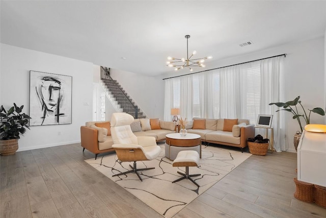 living area featuring a chandelier, wood finished floors, stairs, and baseboards
