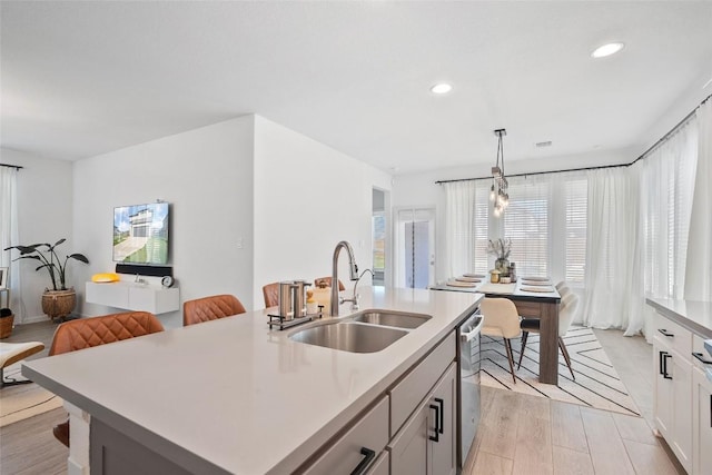 kitchen with a sink, light countertops, dishwasher, recessed lighting, and pendant lighting