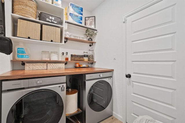 laundry room featuring washing machine and clothes dryer, a dry bar, and wood finished floors