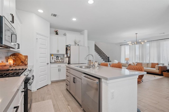 kitchen with stainless steel appliances, a sink, light wood finished floors, a chandelier, and recessed lighting