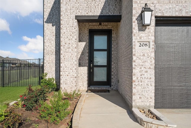 property entrance with fence and brick siding