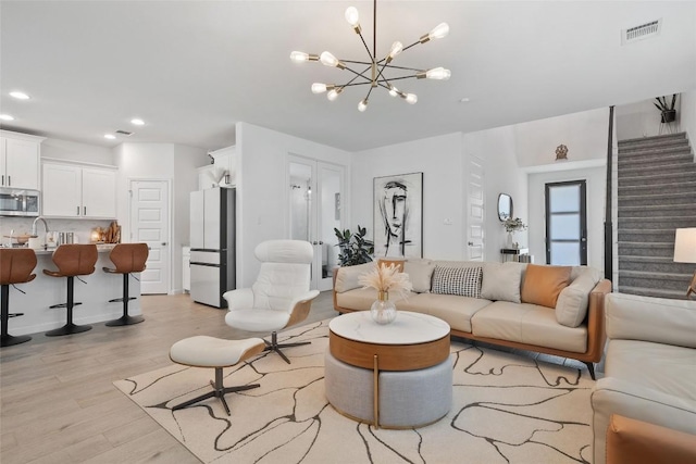 208 Dycus Bnd, Liberty Hill, TX 78642 - living room featuring stairs, light wood-style flooring, a chandelier, and recessed lighting