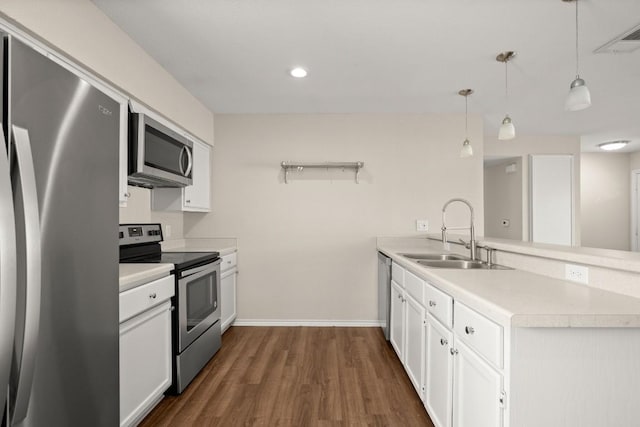 kitchen featuring appliances with stainless steel finishes, a sink, a peninsula, white cabinetry, and recessed lighting