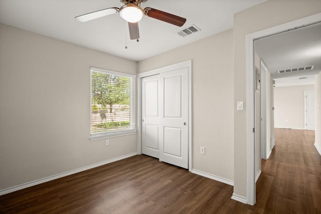 unfurnished bedroom featuring dark wood-style floors, baseboards, a closet, and ceiling fan