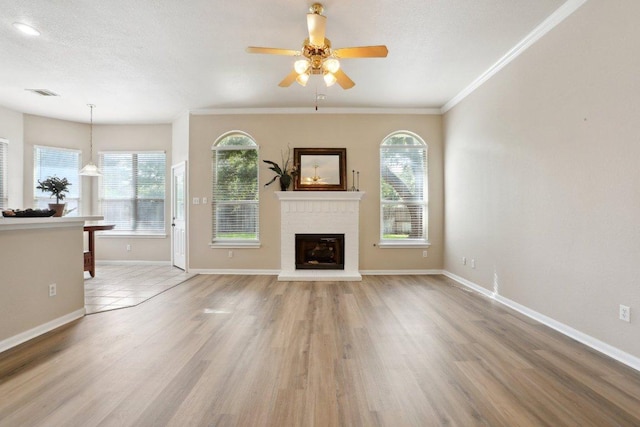 8400 Fern Bluff Ave, Round Rock, TX 78681 - unfurnished living room with ceiling fan, a fireplace, crown molding, baseboards, and light wood-style floors