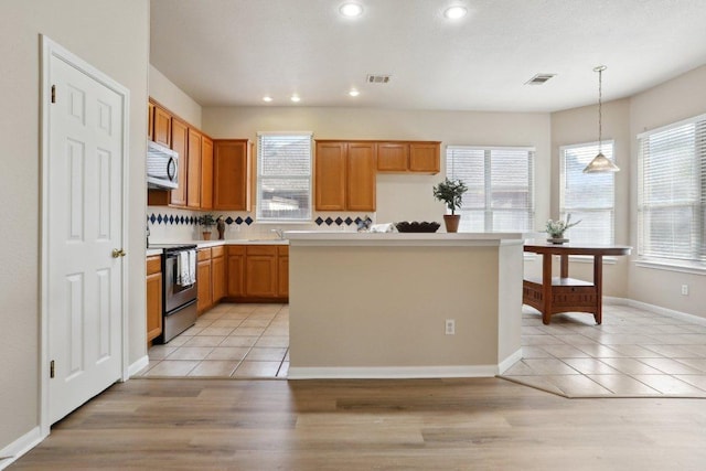 kitchen with appliances with stainless steel finishes, a center island, light countertops, light tile patterned floors, and recessed lighting