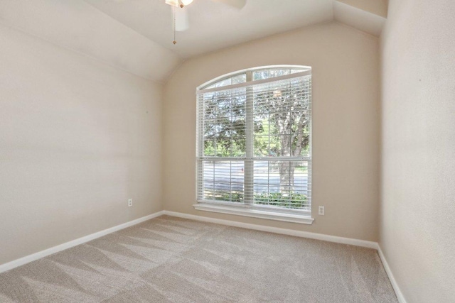 empty room featuring light carpet, vaulted ceiling, ceiling fan, and baseboards