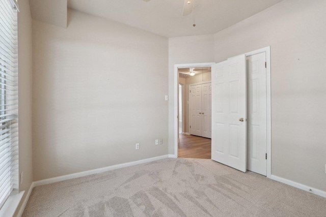 empty room featuring ceiling fan, light carpet, and baseboards