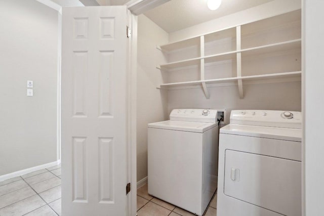 laundry room with washer and dryer, light tile patterned flooring, and baseboards