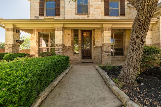 doorway to property featuring a porch and stone siding