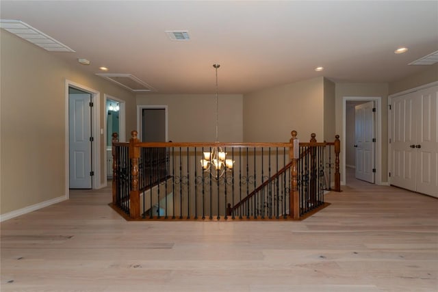 hall with an upstairs landing, attic access, wood finished floors, baseboards, and recessed lighting