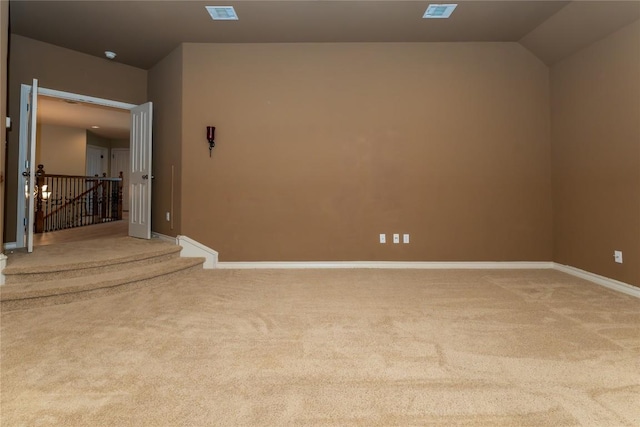 carpeted empty room featuring baseboards and vaulted ceiling