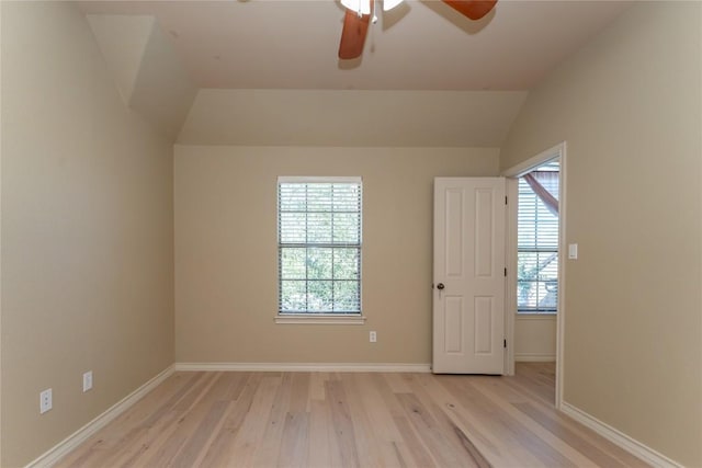 empty room featuring light wood-style flooring, a ceiling fan, baseboards, and vaulted ceiling