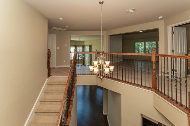 staircase featuring a chandelier, plenty of natural light, baseboards, wood finished floors, and recessed lighting