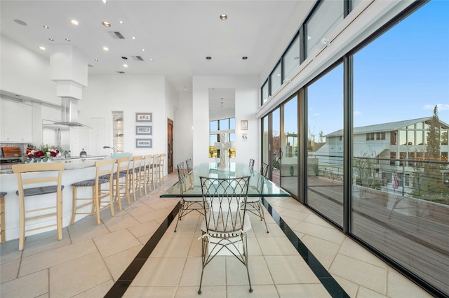 dining space with light tile patterned floors, a towering ceiling, inlaid floor details, and recessed lighting